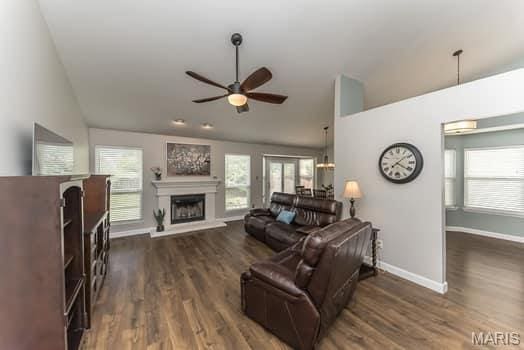 1405 Sunburst Dr, O'Fallon, MO 63366 - living area featuring vaulted ceiling, ceiling fan, a fireplace with raised hearth, and dark wood-type flooring