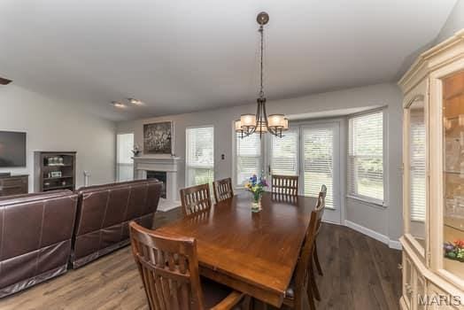 1405 Sunburst Dr, O'Fallon, MO 63366 - dining space with wood finished floors, a chandelier, and a fireplace
