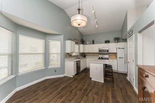 1405 Sunburst Dr, O'Fallon, MO 63366 - kitchen featuring appliances with stainless steel finishes, white cabinetry, light countertops, dark wood finished floors, and high vaulted ceiling
