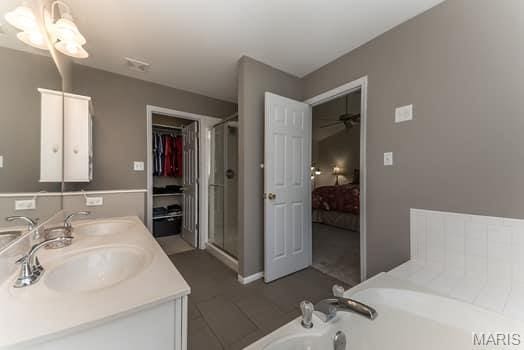 1405 Sunburst Dr, O'Fallon, MO 63366 - full bathroom featuring double vanity, a garden tub, connected bathroom, a shower stall, and a ceiling fan