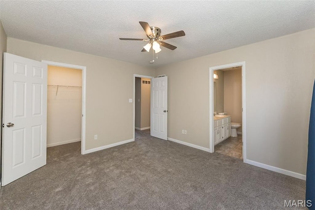 563 Great Plains Dr, House Springs, MO 63051 - unfurnished bedroom featuring a walk in closet, dark carpet, a textured ceiling, ensuite bathroom, and a ceiling fan