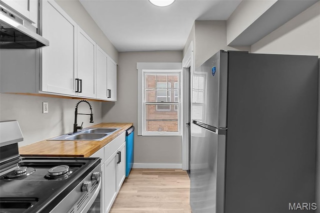 6736 Julian Ave, University City, MO 63130 - kitchen featuring appliances with stainless steel finishes, ventilation hood, light wood finished floors, and white cabinets