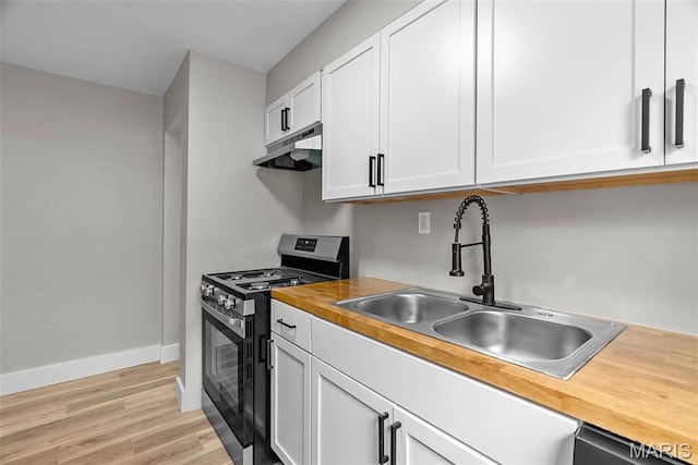 6736 Julian Ave, University City, MO 63130 - kitchen with stainless steel gas range, butcher block countertops, under cabinet range hood, white cabinets, and light wood-style floors