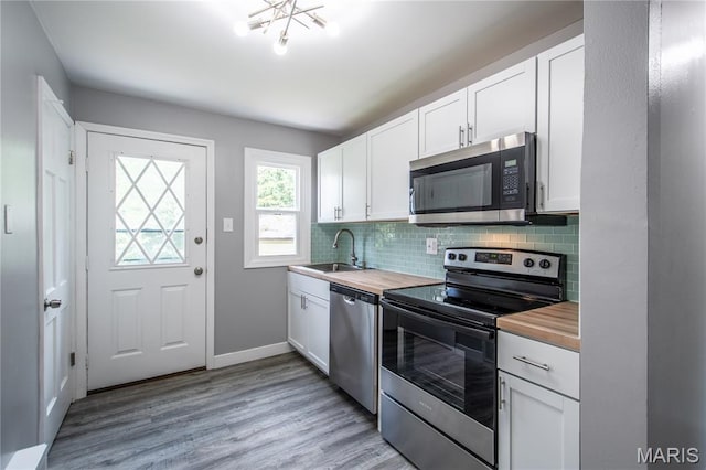 1900 Owen Dr, Hanley Hills, MO 63133 - kitchen featuring stainless steel appliances, butcher block countertops, backsplash, light wood-type flooring, and white cabinetry