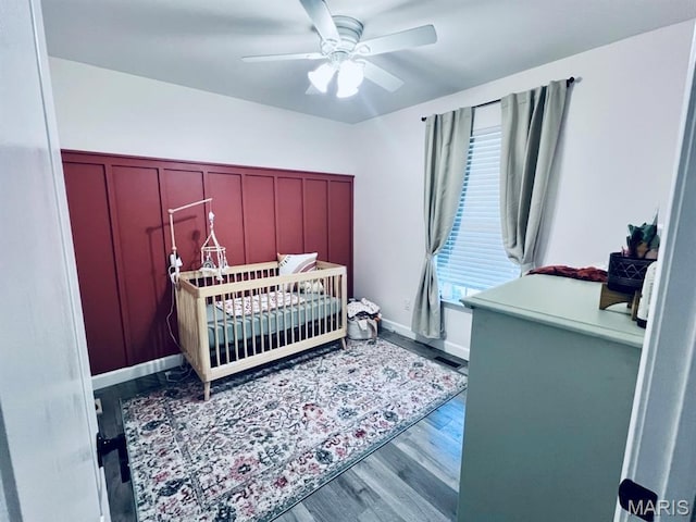 2354 Fountain Dr, Barnhart, MO 63012 - bedroom with wood finished floors, a crib, a wainscoted wall, a decorative wall, and a ceiling fan