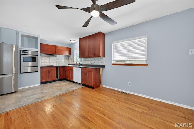 10564 Mert Ave, Saint Ann, MO 63074 - kitchen with appliances with stainless steel finishes, a warming drawer, backsplash, light wood-type flooring, and ceiling fan