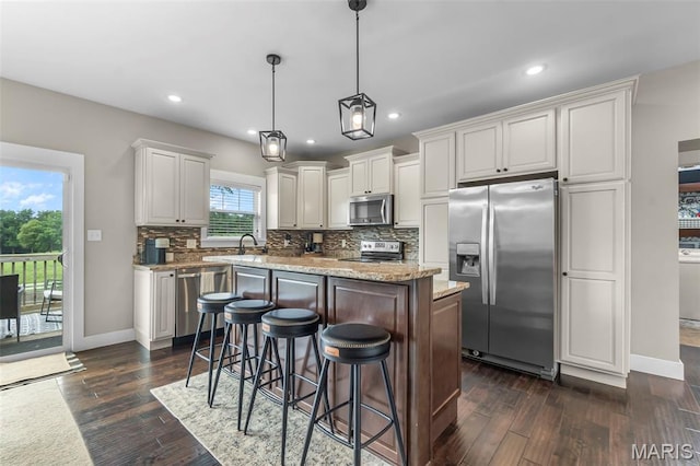 255 Sassenach Dr, Jackson, MO 63755 - kitchen featuring appliances with stainless steel finishes, tasteful backsplash, dark wood finished floors, a center island, and a kitchen breakfast bar