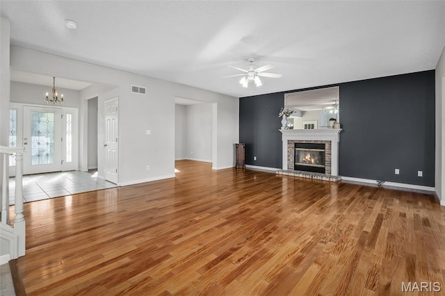 2849 Dardenne Links Dr, Dardenne Prairie, MO 63368 - unfurnished living room featuring a chandelier, a ceiling fan, wood finished floors, and a glass covered fireplace