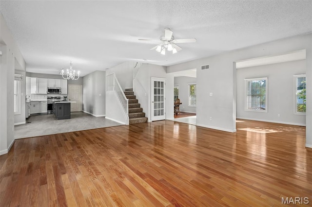 2849 Dardenne Links Dr, Dardenne Prairie, MO 63368 - unfurnished living room featuring stairway, a chandelier, wood finished floors, ceiling fan, and a textured ceiling