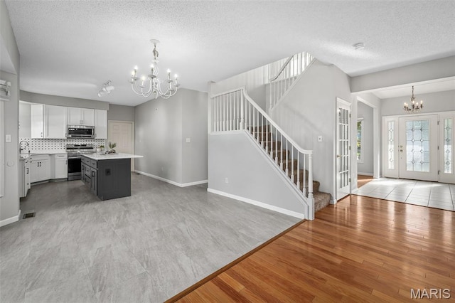 2849 Dardenne Links Dr, Dardenne Prairie, MO 63368 - kitchen featuring appliances with stainless steel finishes, a chandelier, light countertops, a center island, and tasteful backsplash