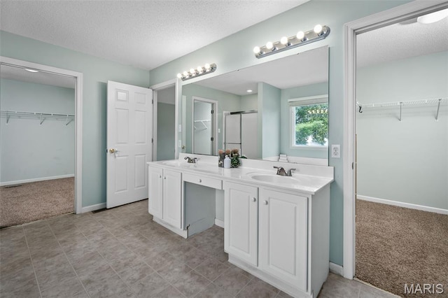 2849 Dardenne Links Dr, Dardenne Prairie, MO 63368 - bathroom with double vanity, a textured ceiling, a shower stall, and a spacious closet