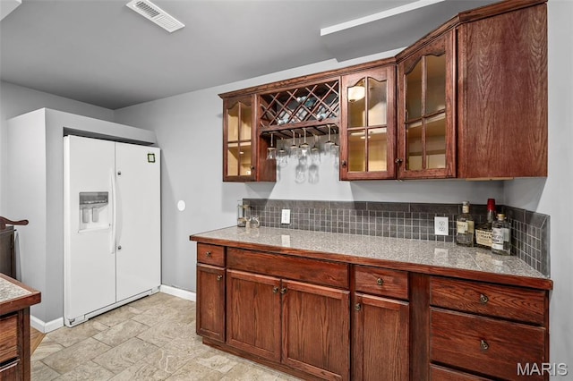2849 Dardenne Links Dr, Dardenne Prairie, MO 63368 - kitchen featuring white fridge with ice dispenser, glass insert cabinets, backsplash, light stone finish floors, and light countertops