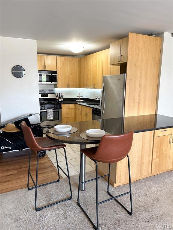210 N 17th St Unit 302, Saint Louis, MO 63103 - kitchen with appliances with stainless steel finishes, dark countertops, light brown cabinets, and light carpet