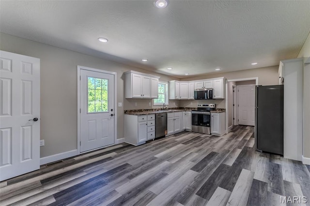 1507 Finn Dr, Lebanon, MO 65536 - kitchen with stainless steel appliances, wood finished floors, white cabinets, recessed lighting, and dark countertops