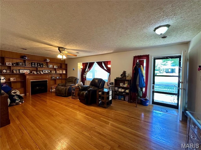 918 E 7th St, Rolla, MO 65401 - living area featuring a textured ceiling, wood finished floors, ceiling fan, and a fireplace