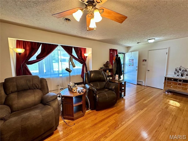 918 E 7th St, Rolla, MO 65401 - living area featuring a textured ceiling, light wood-style floors, a ceiling fan, and baseboard heating