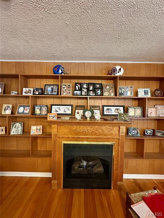 918 E 7th St, Rolla, MO 65401 - detailed view of a textured ceiling, wood finished floors, a fireplace, and wood walls