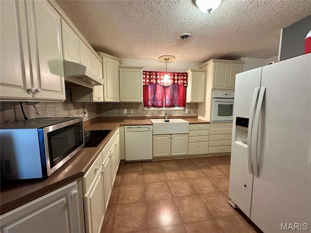 918 E 7th St, Rolla, MO 65401 - kitchen featuring white appliances, under cabinet range hood, tasteful backsplash, a textured ceiling, and dark countertops