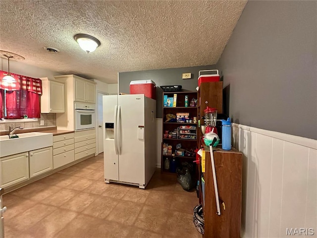 918 E 7th St, Rolla, MO 65401 - kitchen featuring white appliances, a wainscoted wall, a textured ceiling, tasteful backsplash, and white cabinets