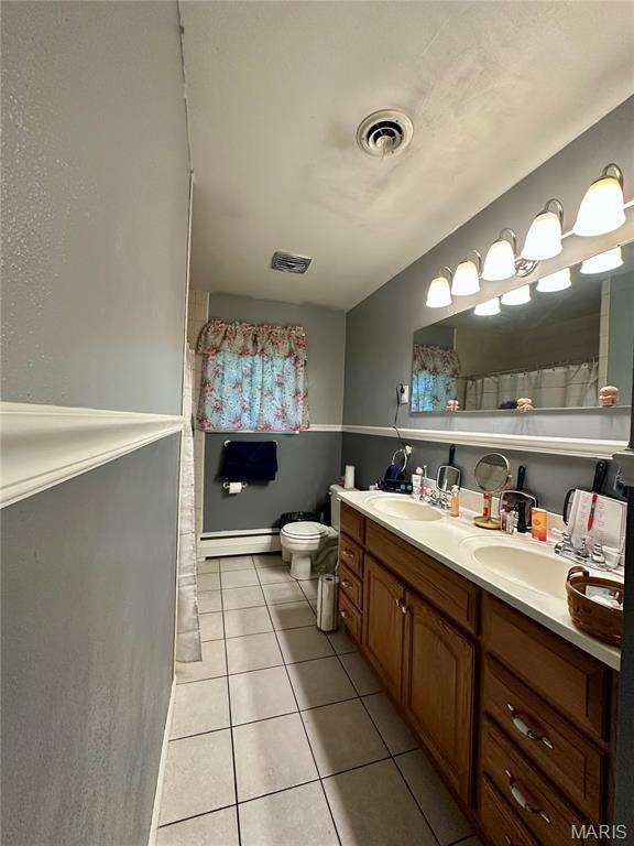 918 E 7th St, Rolla, MO 65401 - full bath with a baseboard radiator, double vanity, tile patterned flooring, and a shower with curtain