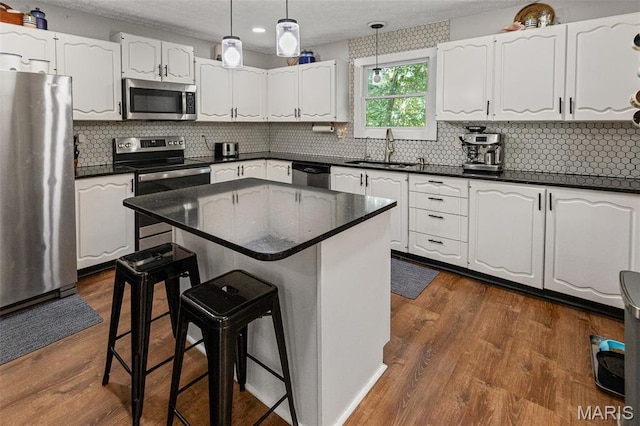 1716 Fountainbleu Dr, Worden, IL 62097 - kitchen with appliances with stainless steel finishes, a breakfast bar, white cabinetry, dark countertops, and a textured ceiling