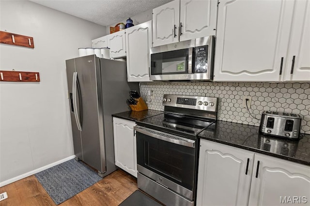 1716 Fountainbleu Dr, Worden, IL 62097 - kitchen with stainless steel appliances, white cabinetry, dark wood-type flooring, decorative backsplash, and a textured ceiling