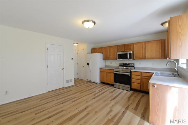 154 Homeshire Dr Unit 27, Wentzville, MO 63385 - kitchen featuring stainless steel appliances, light wood-style floors, light countertops, and brown cabinetry