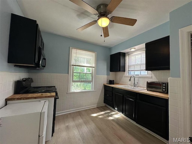 3525 Belaire Pl, Beverly Hills, MO 63121 - kitchen featuring dark cabinets, tile walls, electric range, healthy amount of natural light, and light wood-style flooring