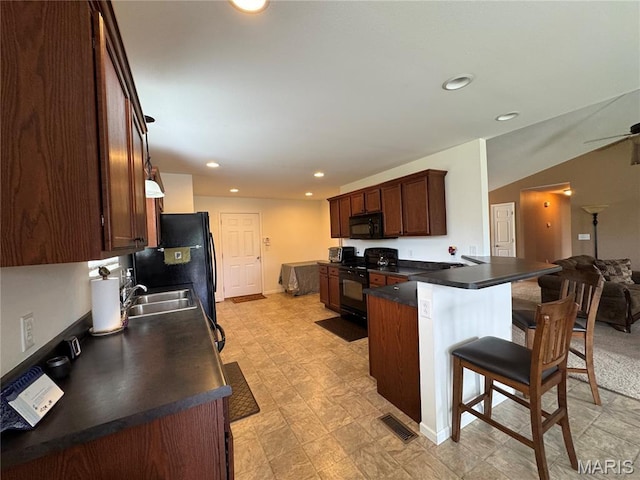 5037 Bristol Hill Dr, Ofallon, IL 62269 - kitchen featuring black appliances, a breakfast bar, a peninsula, dark countertops, and recessed lighting