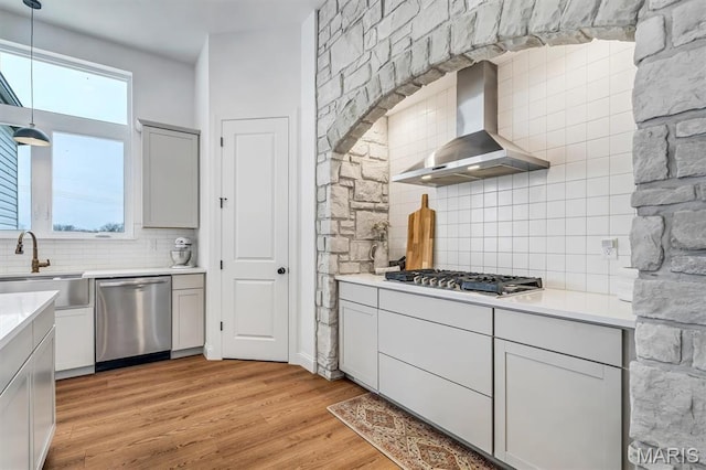 213 Bluegrass Pasture Ct, Wentzville, MO 63385 - kitchen with appliances with stainless steel finishes, wall chimney exhaust hood, backsplash, light wood-type flooring, and light countertops