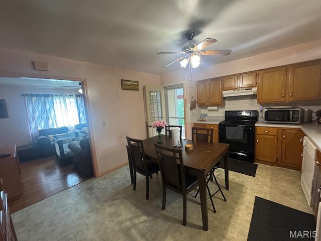 737 Price St, Poplar Bluff, MO 63901 - kitchen with black electric range, under cabinet range hood, stainless steel microwave, and brown cabinetry