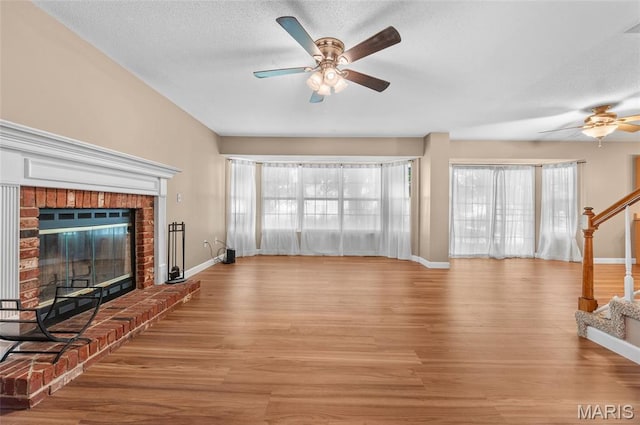 1817 Partridge Pl, Edwardsville, IL 62025 - unfurnished living room featuring a ceiling fan, stairway, light wood-style flooring, a brick fireplace, and a textured ceiling