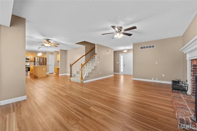 1817 Partridge Pl, Edwardsville, IL 62025 - unfurnished living room featuring a ceiling fan, stairway, a brick fireplace, and light wood-style floors