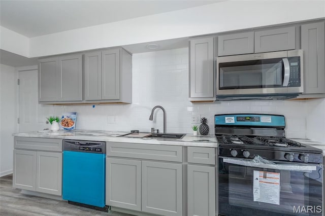 10141 Ventura Dr, Ferguson Township, MO 63136 - kitchen with stainless steel appliances, gray cabinetry, light wood-style floors, and backsplash