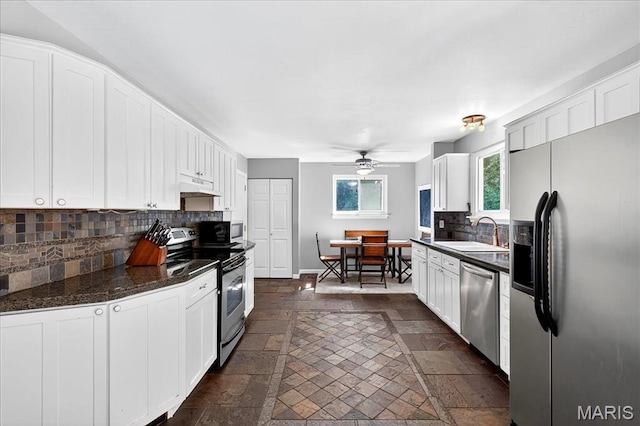 1826 Fairwood Forest Dr, Saint Peters, MO 63376 - kitchen featuring appliances with stainless steel finishes, under cabinet range hood, decorative backsplash, stone tile flooring, and white cabinets