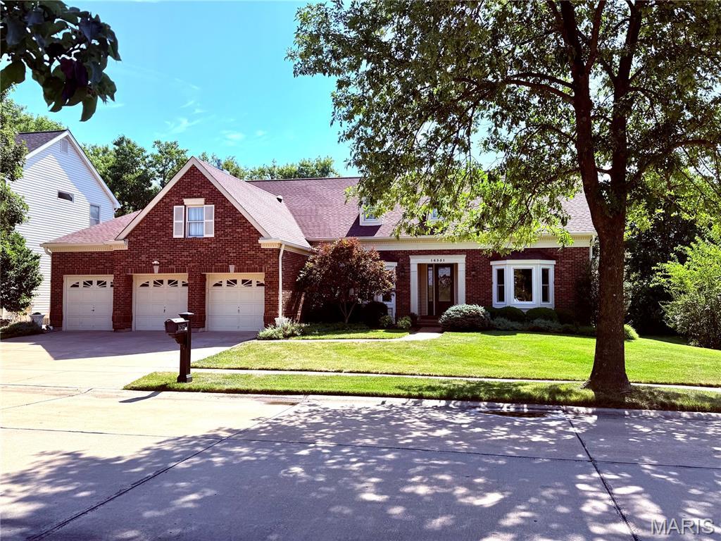 16351 Audubon Village Dr, Wildwood, MO 63040 - view of front of home with brick siding, concrete driveway, a front lawn, a shingled roof, and a garage