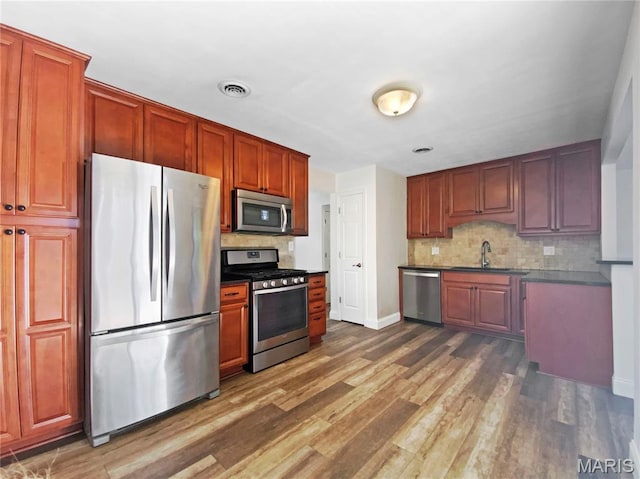 248 Ramsey Ln, Ballwin, MO 63021 - kitchen with appliances with stainless steel finishes, backsplash, dark wood-type flooring, and dark countertops