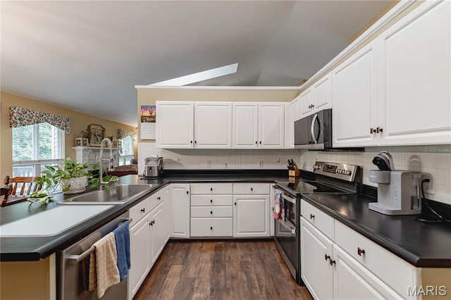 1923 Smizer Mill Rd, Fenton, MO 63026 - kitchen with stainless steel appliances, dark countertops, dark wood finished floors, decorative backsplash, and a peninsula