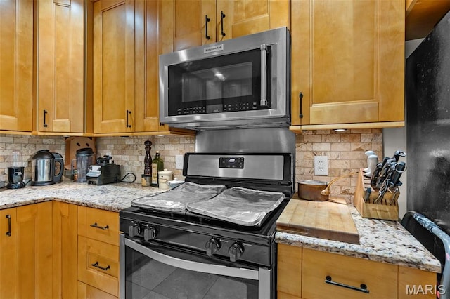 17999 State Highway 177, Jackson, MO 63755 - kitchen with stainless steel microwave, stove, backsplash, and freestanding refrigerator