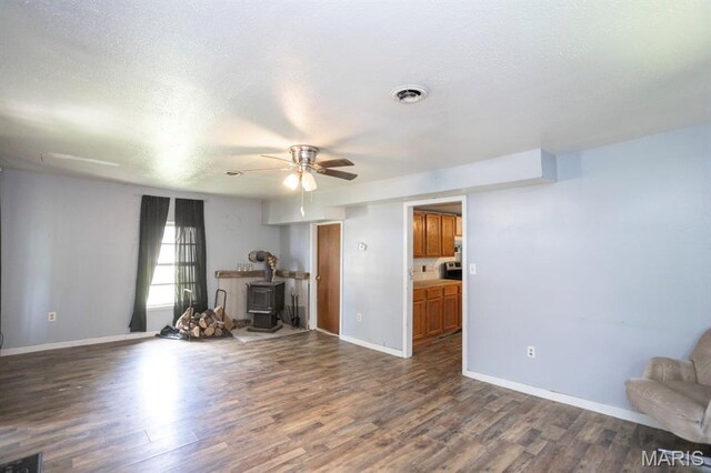 200 S Frisco, Crocker, MO 65452 - unfurnished living room featuring a wood stove, ceiling fan, wood finished floors, and a textured ceiling