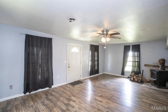 200 S Frisco, Crocker, MO 65452 - unfurnished living room featuring a ceiling fan, a wood stove, wood finished floors, and a textured ceiling