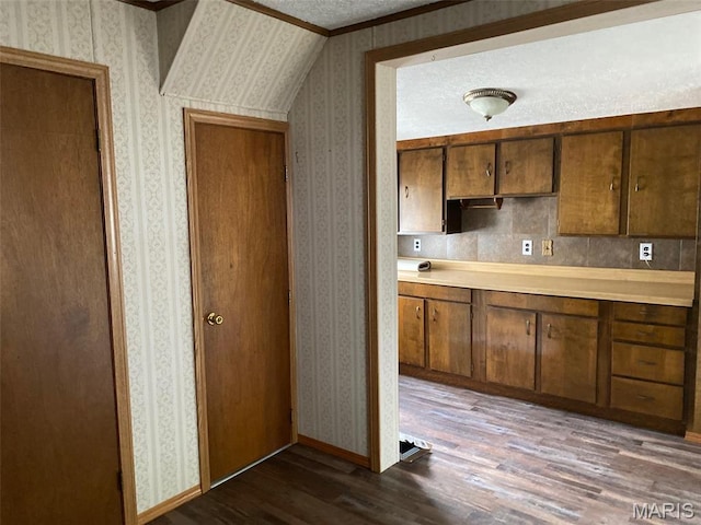 464 S Mill St, Nashville, IL 62263 - kitchen featuring wallpapered walls, dark wood-style flooring, crown molding, light countertops, and brown cabinetry