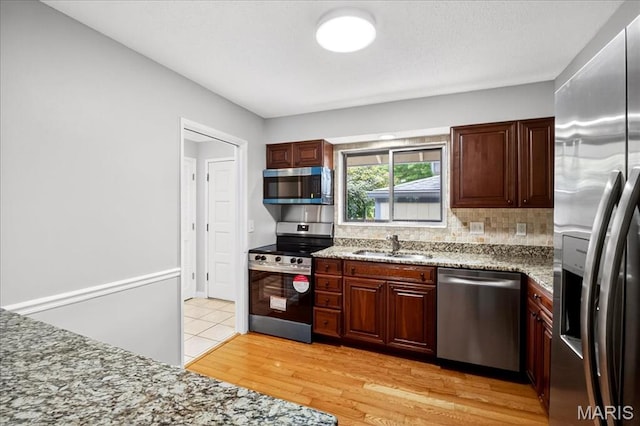775 Knickerbacker Dr, Manchester, MO 63021 - kitchen with appliances with stainless steel finishes, tasteful backsplash, light stone countertops, and light wood finished floors