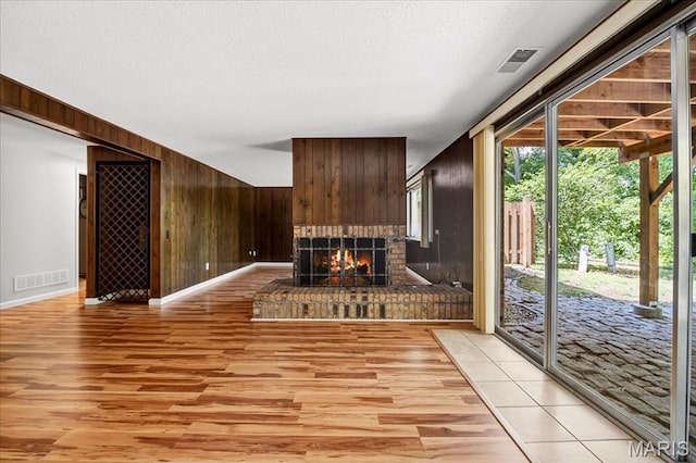 775 Knickerbacker Dr, Manchester, MO 63021 - unfurnished living room featuring wood walls, light wood-style floors, a textured ceiling, and a brick fireplace
