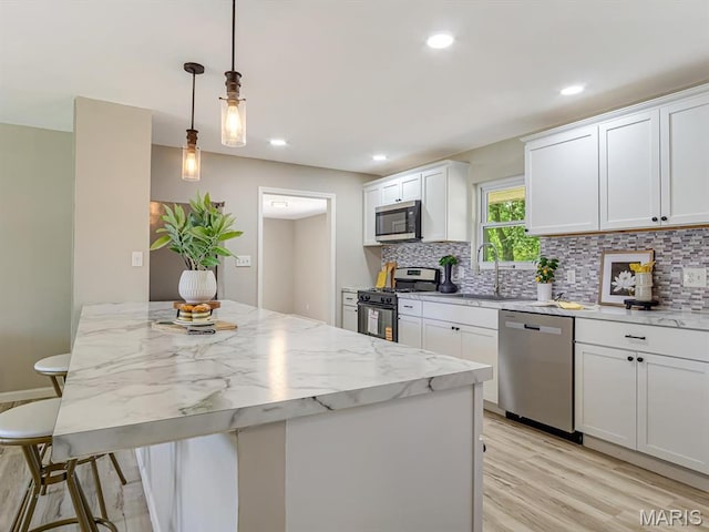 5 Chalet Ct, Fairview Heights, IL 62208 - kitchen with stainless steel appliances, backsplash, white cabinetry, light wood finished floors, and light stone countertops