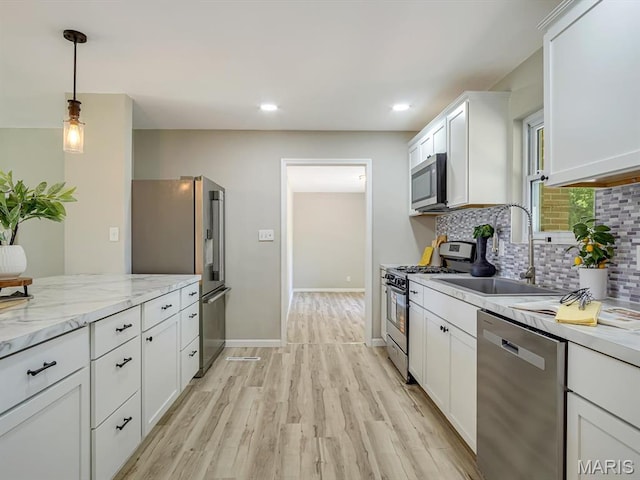5 Chalet Ct, Fairview Heights, IL 62208 - kitchen featuring appliances with stainless steel finishes, decorative backsplash, white cabinets, light wood-type flooring, and pendant lighting