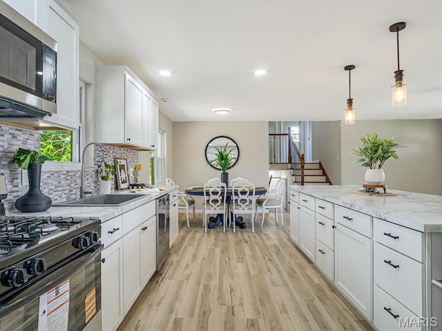 5 Chalet Ct, Fairview Heights, IL 62208 - kitchen with stainless steel appliances, light wood-style floors, backsplash, white cabinetry, and hanging light fixtures