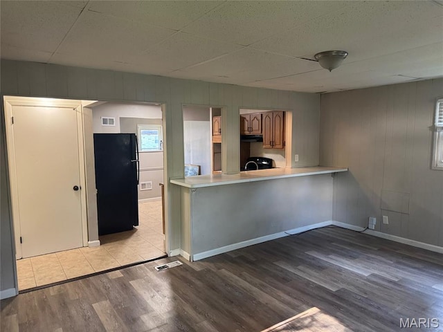 1433 Farmview Ave, Spanish Lake Township, MO 63138 - kitchen featuring freestanding refrigerator, light countertops, wood finished floors, under cabinet range hood, and a peninsula