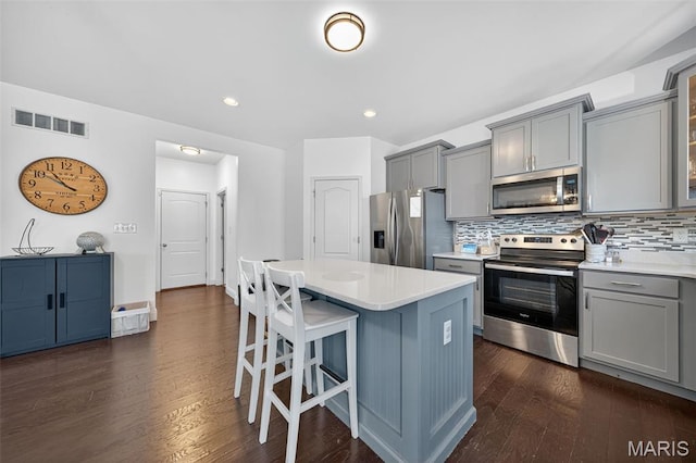 231 Flint Brook Dr, Ofallon, MO 63366 - kitchen with stainless steel appliances, gray cabinetry, a breakfast bar area, backsplash, and light countertops