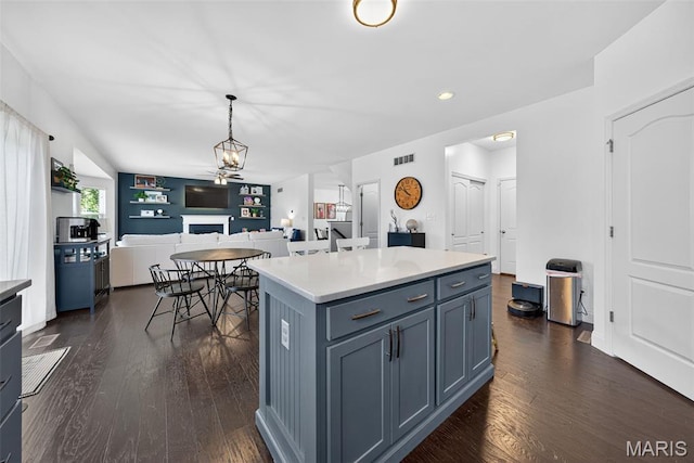 231 Flint Brook Dr, Ofallon, MO 63366 - kitchen with dark wood finished floors, a fireplace, open floor plan, hanging light fixtures, and a center island